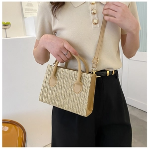 Detail showing herringbone weave texture and brown leather strap on women's square bag