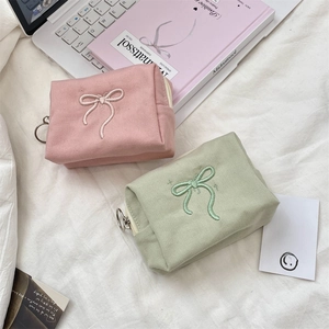 Close-up of bow embroidered canvas mini pouches with circular zipper pulls in pink and green