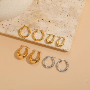 Detail of luxury gold and silver hoop earrings with zircon on a natural stone surface
