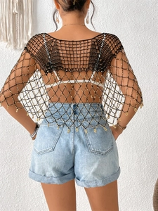 Détail du châle en maille crochet noire avec perles dorées et franges bohèmes transparentes