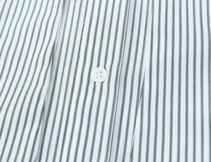 Detail of vertical black stripes on white poplin fabric with white button close-up