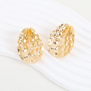 Macro shot of gold teardrop earrings with unique hammered metal texture and wavy base