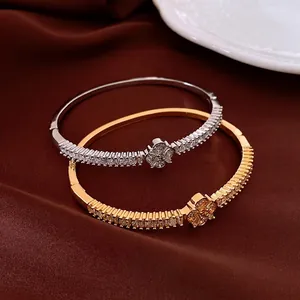 Eleganti bracciali floreali in zircone oro e argento su sfondo di seta marrone
