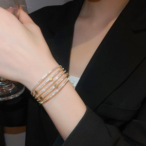 Detail of layered gold bangle featuring parallel bands with sparkling zircon accents