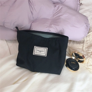 Detail of black canvas makeup bag featuring TIME TO PARTY label on soft fabric texture