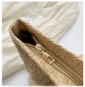 Detail of smooth metal zipper and textured woven straw on a summer bucket beach bag