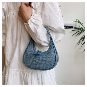 Blue woven hobo bag styled with a white dress on a model in a minimalist home setting