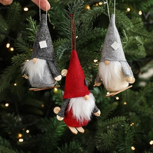 Handmade Christmas gnome hanging ornaments in red and grey felt on a lit tree