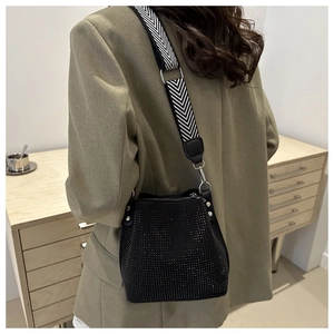 Detail of black rhinestone bucket bag with a chic black and white patterned wide strap