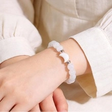 Detailopname van een witte natuurstenen armband met maanhanger om een herenpols