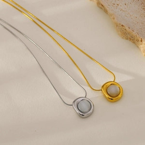 Detailed macro view of gold and silver snake chain necklaces with marble-style stone pendants