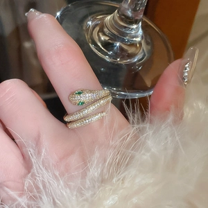 Detailed macro of a gold snake ring with white pavé zircons and green gemstone eyes