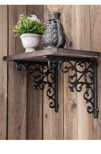 Close-up of vintage floral scrollwork on black cast iron shelf brackets on wood