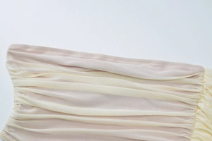 Detailed macro view of the mesh stitching and pleated texture on this pink and beige dress