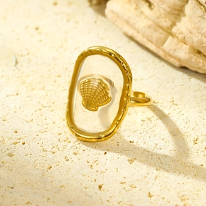 Detail of golden shell embedded in resin on a stylish ocean-themed adjustable ring