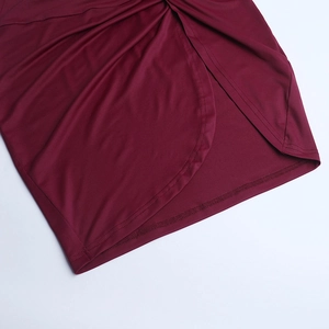Detail of burgundy lace dress showing asymmetric slit hem and high-quality stitch texture