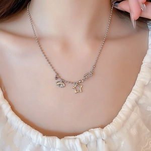 Close-up of silver bead chain necklace with star and wing pendants on woman's neckline