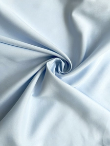 Detail of light blue fabric texture with elegant spiral twist and pleated structure