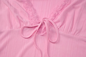 Dettaglio ravvicinato del top rosa con scollo a V, bordo in pizzo e trama del tessuto a coste