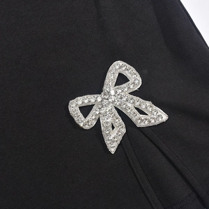 Close-up of sparkling silver rhinestone bow detail on a black split summer dress