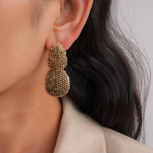 Élégantes boucles d'oreilles goutte en or avec cristaux pavés sur un modèle look luxe