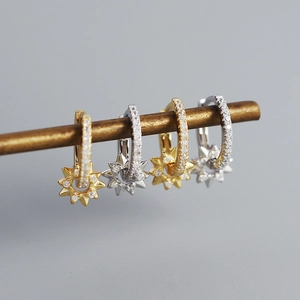 Detail of silver and gold star-shaped hoop earrings with pave-set shimmering crystals