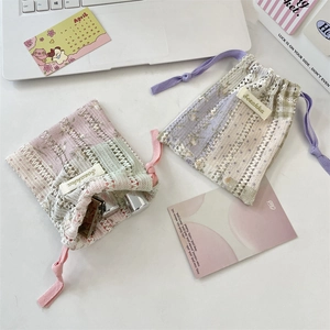 Détail de pochettes à cordon en dentelle florale contenant des cosmétiques sur un bureau