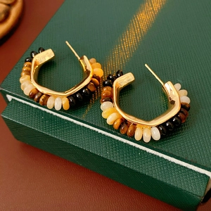Détail de boucles d'oreilles créoles C dorées vintage avec perles sur écrin de luxe