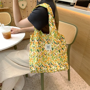 Dettaglio della borsa shopper in tela con stampa di tulipani in un ambiente di caffè