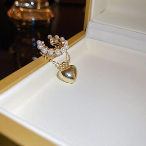 Macro shot of gold heart pendant and pearls on elegant ear cuff over jewelry box
