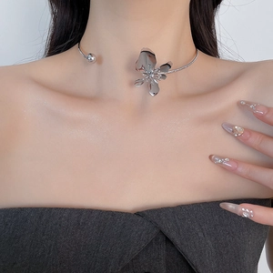 Close-up of a metallic silver flower choker necklace worn on a model's collarbone