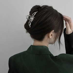 Detail showing a silver metal spider hair claw clip worn on model's hair for Halloween