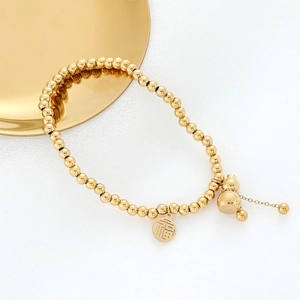 Detail of golden beaded bracelet with traditional Fu character and gourd pendants