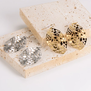 Chic hollow leaf geometric earrings in gold and silver finish on stone background