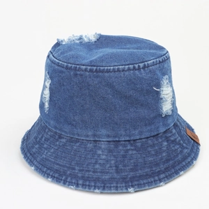 Détail d'un bob en jean délavé avec effets usés et écusson en cuir marron sur le côté