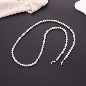 Close-up of white handmade pearl strap with silver lobster clasps on a grey background