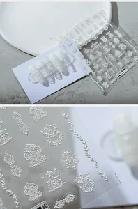Macro detail of 3D embossed white lace flower patterns on transparent nail stickers