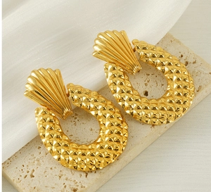 Détails de boucles d'oreilles dorées avec motif coquillage et texture diamantée