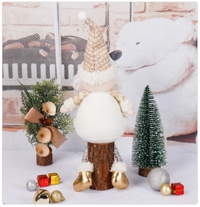 Détail d'un gnome de Noël en peluche blanche assis sur un socle en bois naturel décoratif