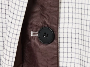 Détail d'un bouton noir sur une veste à carreaux avec doublure en satin brun