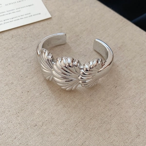 Detailed view of silver open cuff bracelet featuring realistic shell relief on linen fabric