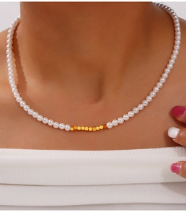 Close-up of pearl necklace featuring gold sugar cube beads worn on a model neck