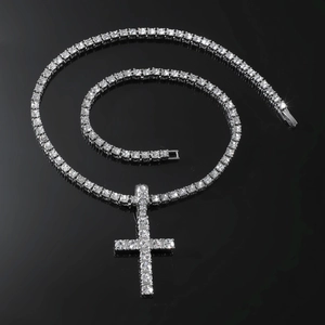 Close-up of sparkling silver cross pendant on a matching iced-out tennis chain necklace