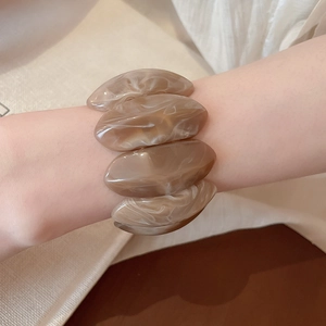Macro shot of marble textured brown and white acrylic elastic bracelet on woman wrist