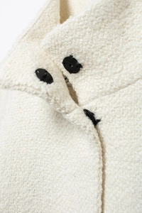 Detailed macro shot of white tweed fabric texture and black buttons on this elegant coat
