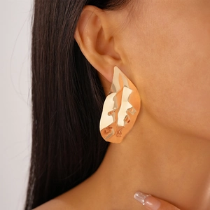 Detailed close-up of metallic textured leaf earrings in gold finish on female model
