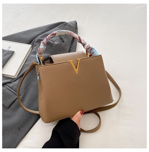 Stylish brown leather crossbody bag with chic V logo, scarf handle and elegant design.
