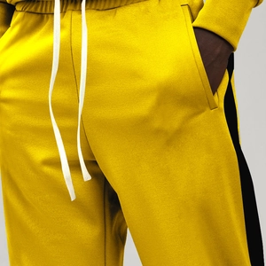 Detail of yellow joggers featuring black side stripes and white drawstring waist cord