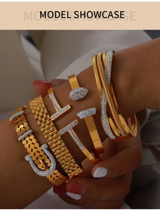 Detail showing stacked gold titanium bracelets with T-shaped crystals and buckle design