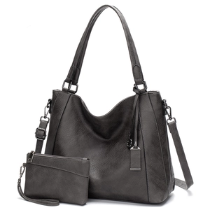 Detail of dark gray textured leather tote bag set with matching pouch and metal hardware
